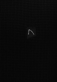 Tessuto nero testurizzato con un motivo a griglia, caratterizzato da una piccola patch nera con un disegno a linea bianca. Dettagli di design semplici e minimalisti.