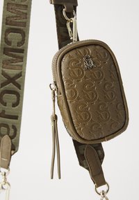 Brun tekstureret mini taske med præget logo, guldfarvet hardware og justerbar camo-strop med kontrasterende bogstaver. Lynlås lukning med frynse.