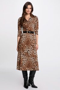 Robe imprimée léopard avec un col, des manches longues et une ceinture noire. Tissu lisse et design mi-long associé à des bottes à talons noires.
