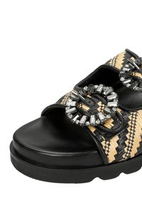 Sandali a wedge neri e beige in materiale intrecciato, con due decorazioni circolari di grande impatto e una suola nera testurizzata.