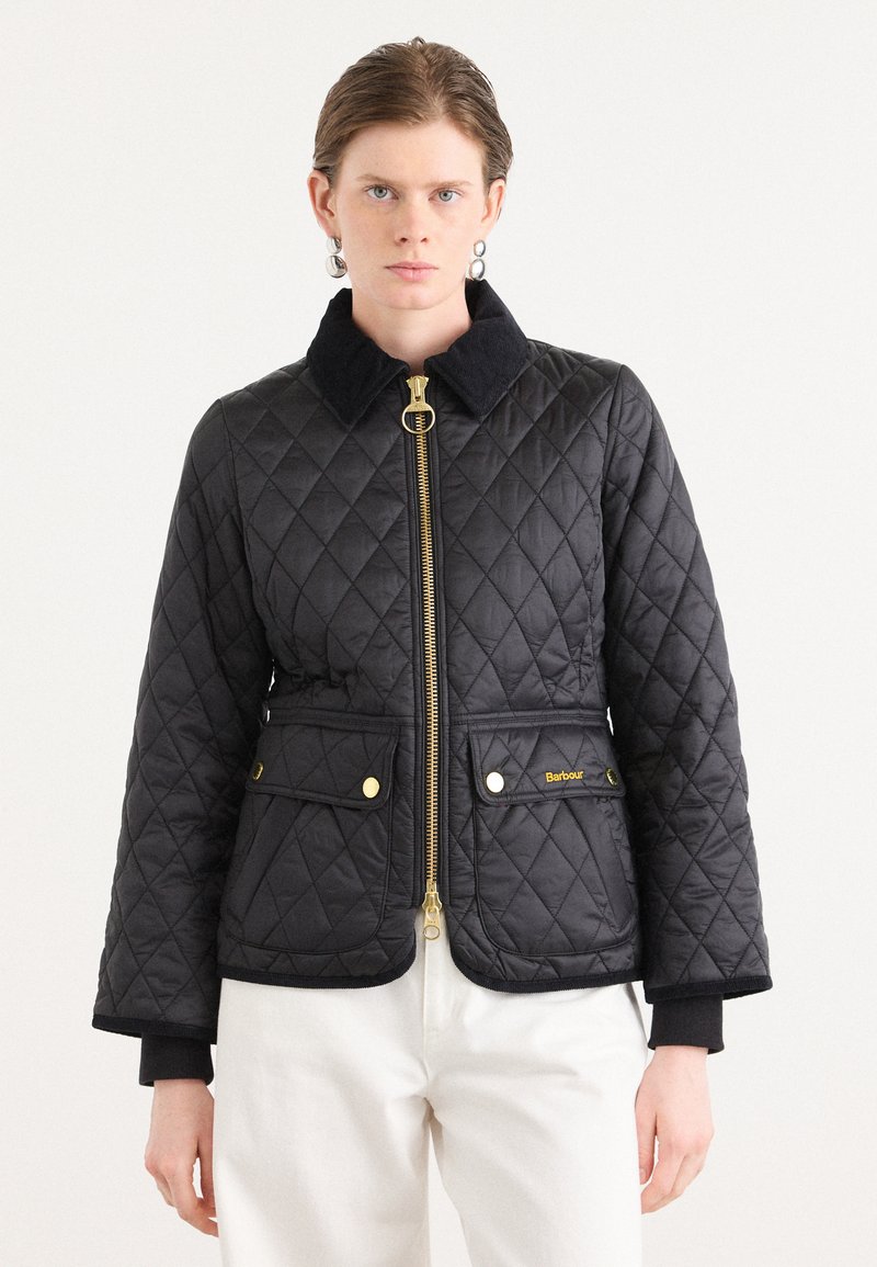 Zwarte gewatteerde jas met een gouden ritssluiting, drukknoopzakken en een ribstoffen kraag. Heeft een getailleerd ontwerp en contrasterende manchetten. Minimale branding zichtbaar.