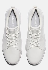 Para białych sneakersów Timberland z sznurówkami widziana z góry na białym tle.