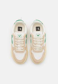 Sneakersy Veja z beżową skórą zamszową i białą kanwą, zielonymi akcentami logo oraz perforowanym czubkiem. Posiadają białe sznurowadła i wkładkę z logo.