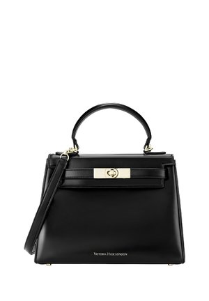 Person i rød ribstrikket sweater, der holder en sort Victoria Hyde London håndtaske med guldlås og håndtag.