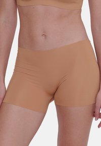 Naadloze naakte shorts gemaakt van zachte, rekbare stof. Heeft een middelhoge taille en een glad, minimalistisch ontwerp zonder zichtbare naden.