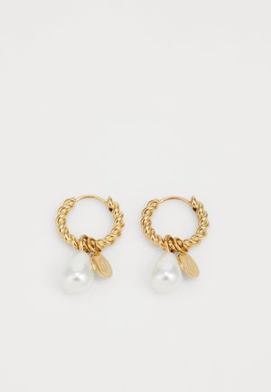 Boucles d'oreilles en or avec un design torsadé, comportant une perle blanche en forme de goutte et un petit charm circulaire.