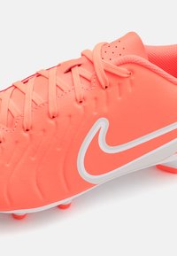 Bright pink soccer cleat with textured synthetic upper, white logo accent, and matching laces. Features small raised patterns and studded sole.