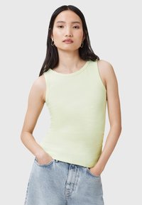 Top sin mangas de color verde claro en un estilo ajustado, fabricado con un material suave de textura lisa y escote redondeado. Presentado con pantalones cortos de denim.