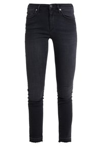 Jeans ajustados negros de mezclilla, con cintura alta, dos bolsillos frontales, dos bolsillos traseros y un dobladillo deshilachado en el tobillo.
