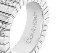 Sølvring med ribbet design og glitrende steiner. Gravet "Calvin Klein" på den indre delen av ringen. Glatt tekstur generelt.