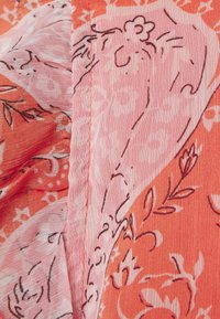 Tejido con estampado que presenta tonos naranjas y rosas con diseños florales; ligero, texturizado y cosido en los bordes.