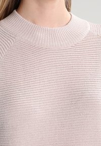 Helles rosa, gestricktes Sweatshirt mit einem gerippten Kragen und horizontalem strukturiertem Muster; verfügt über Raglanärmel und eine weiche, gewebte Oberfläche.