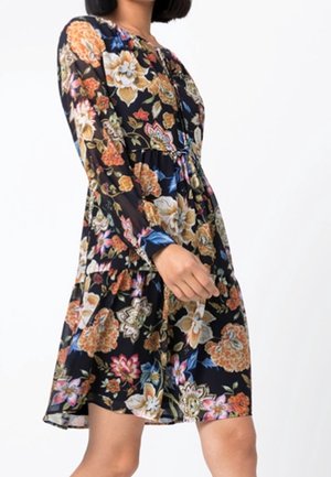 Zwarte bloemenjurk met lange mouwen, een aangesloten lijfje en een uitlopende rok. Het patroon bevat grote bloemen in oranje, blauwe en roze tinten.