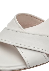 Hvide lædersandaler med et krydsende stropdesign. Glat tekstur og diskrete syninger, med en flad sål med en naturlig finish.