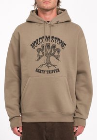 Bruine hoodie met een grafische print van een boompje, tekst "VOLCOM STONE EARTH TRIPPER," kangoeroezak en een kap met trekkoord.