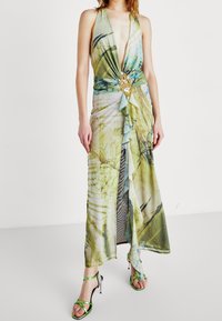 Lång, flödande klänning i ljusgrön och blå blommig tryck med djup V-urringning, åtsittande midja och dekorativt i guld.