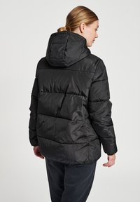 Zwarte pufferjack met horizontaal gestikte secties, een aansluitende capuchon en elastische manchetten. Matte afwerking en synthetisch materiaal.