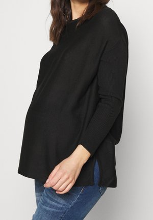 Black knit maternity sweater featuring long sleeves, a relaxed fit, and side slits. Soft texture with a smooth finish. Suitable for layering.