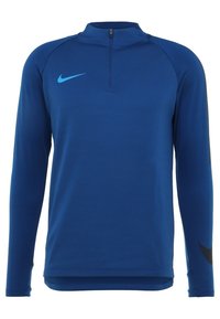 Top atletico blu a maniche lunghe con colletto a mezza zip, caratterizzato da un piccolo logo turchese e dettagli neri lungo le maniche. Texture liscia.