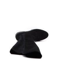 Bottine en daim noir avec une tige large et un bout légèrement pointu. Caractérisée par une semelle texturée et un détail de couture minimal.