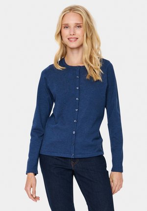 Cardigan lungo blu navy con scollo rotondo, chiusura a bottoni e texture liscia. Indossato sopra jeans di denim scuro.