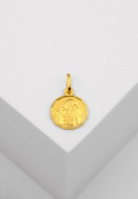 Pendentif en or, forme octogonale, présentant une figure sculptée avec des ailes. Surface lisse et polie, attachée par une petite boucle pour la suspension.