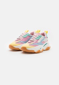 Zapatillas coloridas con paneles de malla en rosa y azul, una puntera amarilla y una suela gruesa con acentos naranjas. Incluye cordones y bucles de agarre.