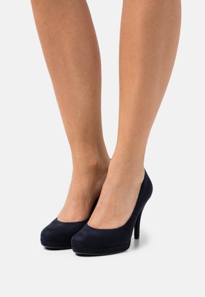 Escarpins en daim bleu marine à talon haut avec bout rond et semelle à plateforme. Le talon est élégant et effilé. Texture lisse, design moderne.