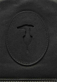 Schwarze Lederbörse mit geprägtem rundem Logo-Design, glatter Textur und Reißverschluss mit metallischen Akzenten entlang der Kante.