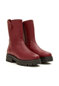 Botas de tobillo de cuero burdeos con un acabado suave, cremallera lateral y suela de goma negra gruesa con un patrón de relieve.