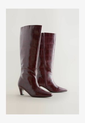 Burgundowe skórzane kozaki sięgające do kolan z teksturą krokodyla, w szpic, z średnim obcasem. Posiadają zamek błyskawiczny z boku.