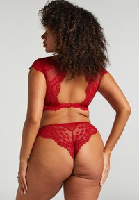Rode kant lingerieset met een low-back beha met korte mouwen en bijpassende string, beide met bloemmotieven en doorzichtige texturen.
