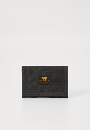 Black nylon wallet with a fold-over design, featuring a yellow logo patch and stitched edges. Textured fabric with a subtle pattern.