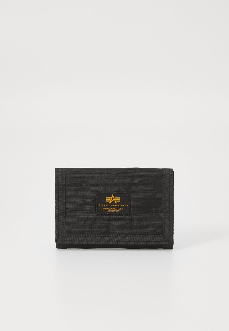 Black nylon wallet with a fold-over design, featuring a yellow logo patch and stitched edges. Textured fabric with a subtle pattern.