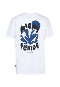 Bílá bavlněná tričko s výrazným grafickým designem, na kterém je napsáno "Miami Florida" v černé a modré barvě, doplněné abstraktními tvary.