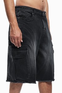 Homme portant un short cargo en denim noir avec de grandes poches latérales et des ourlets effilochés, montré de la taille aux genoux sur fond blanc.