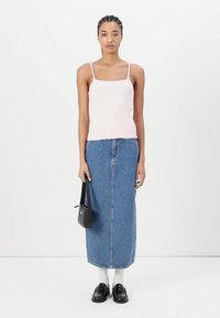 Lys rosa tanktopp med tynne stropper, sammen med et knelengde blått denimskjørt. Modellen holder en liten svart håndveske og har på seg hvite sokker med sko.
