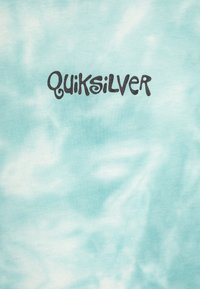 Τυπωμένο μπλουζάκι σε τιρκουάζ χρώμα από βαμβάκι, με το μαύρο λογότυπο "Quiksilver" σε στυλιζαρισμένη γραμματοσειρά κεντραρισμένο στο μπροστινό μέρος.