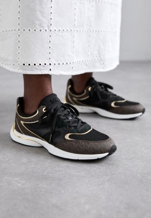 Scarpe da ginnastica nere e marroni con mesh e pelle texturizzata, dettagli dorati e suola bianca. Presentano lacci e un logo sul lato.