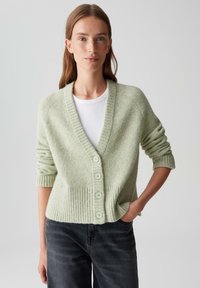 Lichtgroene cardigan met geribbelde zoom en manchetten, met een V-hals, vijf knopen en een zachte textuur, gestyled over een witte top.