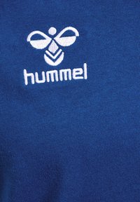Weiß gesticktes Hummel-Marken-Bienenlogo und Text auf blauem Strickstoff.