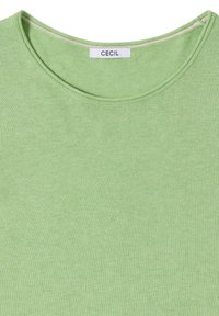 Pull vert clair à col rond avec une étiquette de marque blanche "Cecil" cousue à l'intérieur du col.