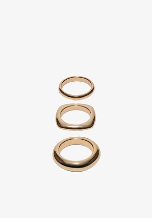 Three gold rings with different shapes: a thin round band, a rounded square band, and a thick rounded round band on white background.