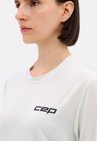 Light mint green athletic shirt with a round neckline, mesh texture, and black "CEP" logo on the front. Sleeves are short and fitted.