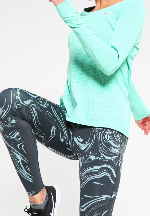 Lettet mintgrøn langærmet atletisk top med tekstureret stof, parret med tætsiddende sorte leggings med et virvle mønster i teal.