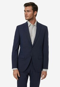 Marineblauer Anzug aus strukturiertem Stoff, einreihiges Design, zwei Knöpfe, Reverskragen, kombiniert mit einem gestreiften Hemd darunter.