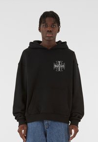 Sort hætte sweatshirt lavet af blødt materiale, med en front kangaroo lomme og et grafisk logo i hvidt på brystet.