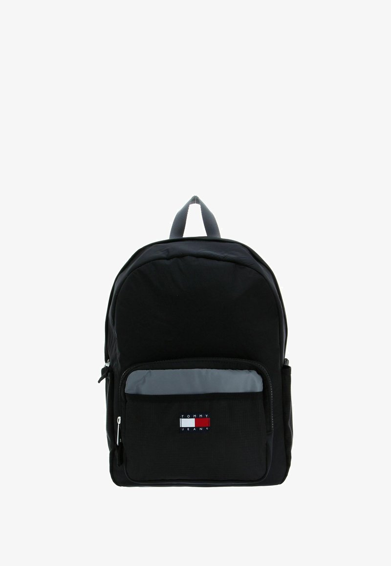Sac à dos en tissu noir de forme arrondie, avec une poche avant zippée et des accents gris. Logo Tommy Jeans affiché sur la poche.