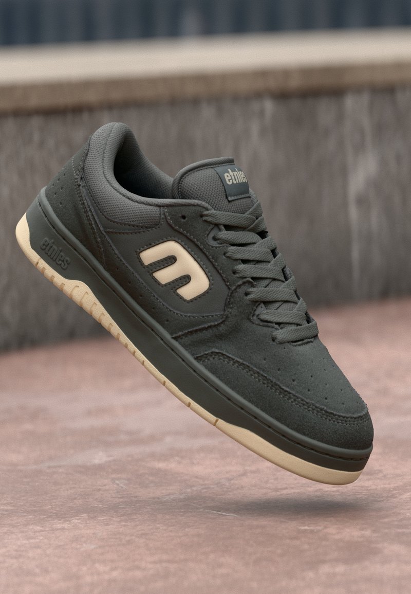 Temnozeleni semiš športni čevlji s teksturiranim finišem, smetana akcenti na logotipu in podplatu, z zaobljenim prstom in vezalnim dizajnom.