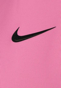 Rosa Sportstoff mit vertikalen Rillen, versehen mit einem auffälligen schwarzen Nike-Swoosh-Logo. Das Material wirkt glatt und leicht.